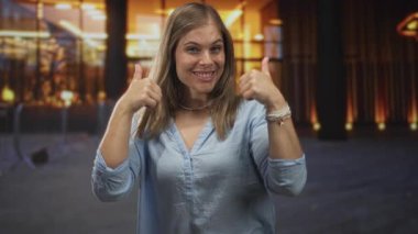 Mavi gömlekli sarışın kadın bina girişinde başparmak kaldırıyor; iyimserlik, güven, enerji tatmini..
