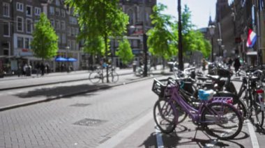Ağaçların ve binaların bulunduğu bulanık Amsterdam caddelerinde bisikletler Hollanda 'da güneşli bir gökyüzünün altında bokeh etkisi yaratıyor..