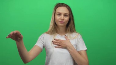 Yeşil izole edilmiş bir arka plana karşı duran beyaz gömlekli bir kadının el kaldırışı samimiyet duygusu ve doğruluk sözü yaratıyor..