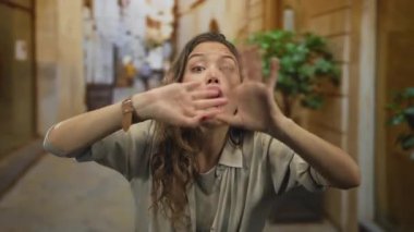 Açık ağızlı, dışarıdaki kamerayı işaret eden genç İspanyol kadın, acil iletişim..