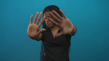 Örgülü saçları ve elleri olan Afro-Amerikalı kadın avuçlarını kaldırıp siyah gömlek ve mücevherlerle stüdyoya gitti..