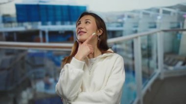 Düşünceli bir pozla bir yolcu gemisinde gülümseyen kadın, açık hava manzarasını seyrederken açık hava manzarasının keyfini çıkarıyor..