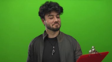 Sakallı genç adam kırmızı panoyu tutarken canlı yeşil arka plana karşı hislerini ve ifadesini İspanyol erkeklerinde gösteriyor.