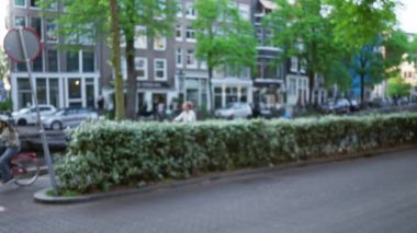 Arka planda bulanık binalar ve arabalar olan Avrupa şehir caddesinin Bokeh manzarası, kaldırım taşları üzerinde yemyeşil çizgiler, sakin bir kentsel atmosfer yaratıyor..