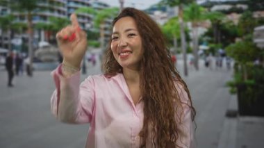 Genç kadın gülümserken ve kameraya yaslanırken meşgul şehir caddesini işaret ediyor; neşe dolu güven.