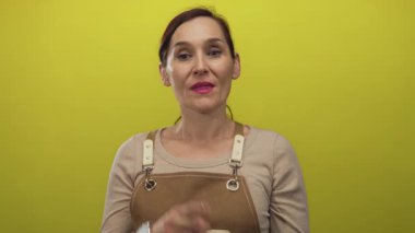 Sarı duvarlı bir fotoğraf stüdyosunda telefon görüşmesi yapan Latin kökenli genç bir kadın..