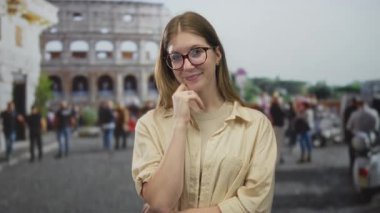 Bej gömlekli genç sarışın kadın kolezyum tarafından el ele çene dokunur; merak.