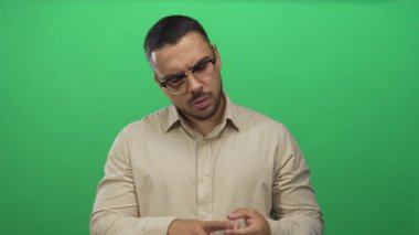 Stüdyodaki parlak yeşil duvara karşı parmaklarını sayan genç adam 1 'den 5' e kadar işaret ediyor; tefekkür.