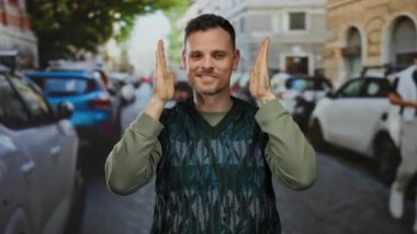 Arka planda arabaları olan, şehir atmosferinde mutluluk ve canlılık gösteren, neşeli hareketler yapan genç bir adam..