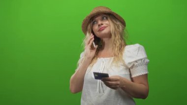 Stüdyoda elinde kredi kartıyla akıllı telefonu tutan kadın, düşünceli bütçe planlaması..