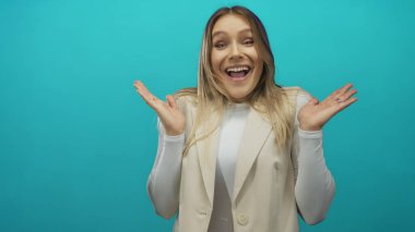 Parlak yeşil bir arka plan karşısında şaşıran bir kadın, şok ve heyecan sergiliyor, sarı saçlı ve beyaz tenli, stok fotoğrafçılığında etkileyici ve duygusal senaryolar için mükemmel..