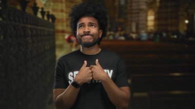 Güvenlik üniformalı bir adam kilisenin içinde düşünceli ya da gergin görünüyor. Dini bir ortamda düşünceli bir ifadeyle..