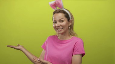 Tavşan kulaklığı takan, gülümseyen ve stüdyoda avuçlarını açan bir kadın..