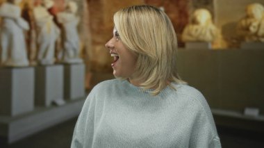 Açık gri kazaklı, ağzı açık bir kadın müzedeki klasik mermer heykele bakıyor..