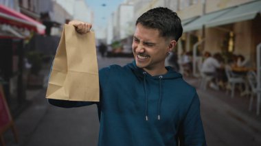 Latin kökenli genç adam şehir sokaklarında mavi kapüşonlu bir kapüşonlu giyerken başarıyı ve mutluluğu yakalıyor..