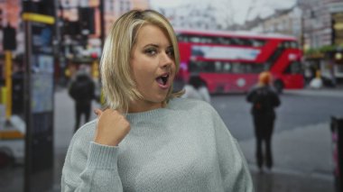 Genç sarışın kadın kırmızı otobüs ve trafik ışıkları yakınlarındaki işlek şehir caddesinde boğazını kesiyor. Tehdit uyarısı..