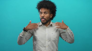 Çizgili gömlekli adam ateşli görünüyor. Parlak yeşil bir arka plana karşı kendini yelpazeleyerek mizahi bir ısı ifadesini somutlaştırıyor..