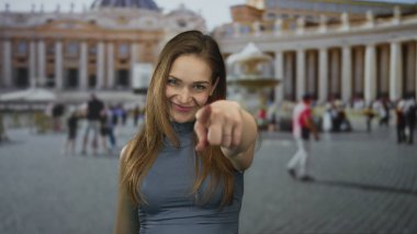 Kadın, Vatikan St. Peter Meydanı 'ndaki fıskiyeli sütun binasına parmağıyla işaret ediyor..