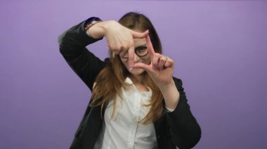 Genç bir kadın mor stüdyo ortamında gözlük ve blazer çerçeve sahnesi takıyor..