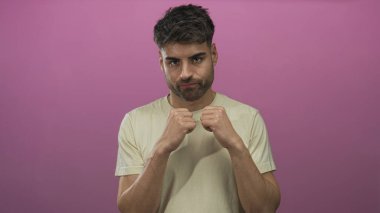 Genç İspanyol bir adam parlak pembe bir stüdyoda yumruklarını sıkmış bir boks yumruğu atıyor. Kararlılık cesareti..