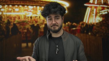 Geceleri açık havada sakallı genç bir adam aydınlık arabalarla çevrili dalgın dalgın dalgın bakıyor neşeli ama içsel bir atmosfer yaratıyor..