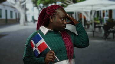 Şehrin dışındaki terasta Dominik bayrağı jestleri olan kadın.