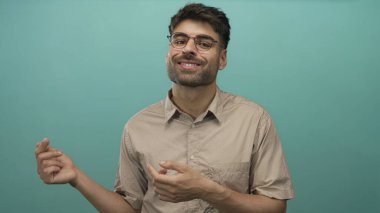 Gözlüklü ve bej tişörtlü bir adam nane atölyesine bakarken parmağıyla elini gösteriyor. Sürpriz..