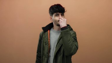 Yeşil ceketli genç adam kahverengi arka planda şef öpücüğü veriyor izole edilmiş portre tarzı.