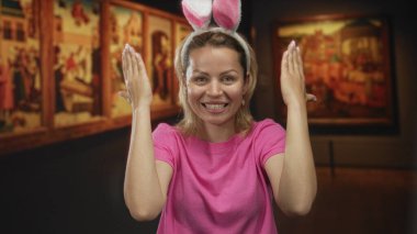 Gözleri tavşan kulaklığı takan ve sanat galerisinde gülümseyen bir kadın..