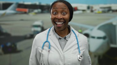 Havaalanı terminalinde gülümseyen steteskoplu kadın doktor sağlık hizmeti teması sergiliyor..