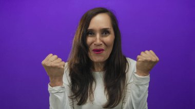 İspanyol kadın bir stüdyo ortamında mor bir duvara karşı iki eliyle gözlerini kapatır; sürpriz şaşkınlık merak.