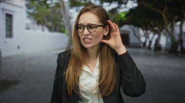 Gözlüklü ve siyah ceketli kadın şehir avlusunda dar kaşlı kaş ile el ele tutuşuyor..