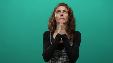 Yeşil arka plan duvarına karşı gözlerini kapamış dua eden kadın, içsel gözlem ve yalnızlığı ima ediyor. Huzuru ve gençliği kapsayan sakin bir ortamda..