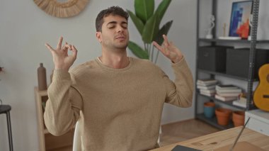 Adam dizüstü bilgisayarın üzerine eğilip bilgisayarda çalışan Latin kökenli genç bir kullanıcı olarak rahat bir duruşta jesti kaldırıyor..