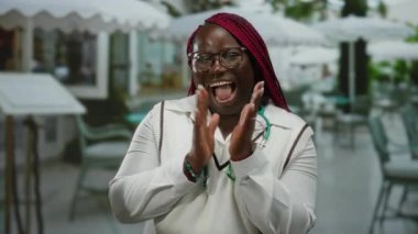 Bir kadın steteskopla şehir restoranında el çırpıyor ve gülümsüyor..