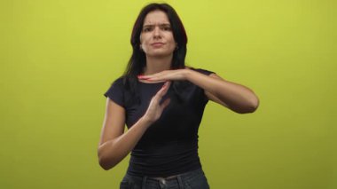 İspanyol genç kadın elleri, parlak yeşil stüdyoda gergin bir ifadeyle zaman aşımı jesti oluşturur..