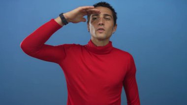 Kırmızı balıkçı yaka kazaklı adam mavi stüdyoda alından alnına gölgelik gözler; merak keşfi.