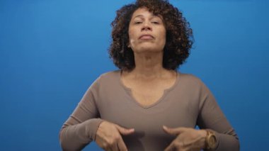 Elleri göğsüne yakın olan bir kadın stüdyoda yavaşça nefes alma egzersizi yapıyor..