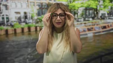 Elleri yanaklı gözlüklü bir kadın Amsterdam 'da kanal kenarında tepkimeye girdi..