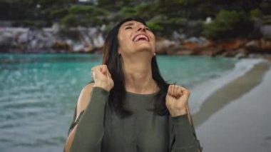 Orta yaşlı İspanyol kadın yumruklarını sıkmış ve stüdyoda gülümsüyor; sevinç güçlendirme iyimserliğini kutluyor.