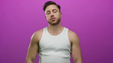 Sakallı genç bir adam, parmaklarıyla canlı pembe bir arkaplan üzerinde beyaz bir atlet, duygularını kapalı gözlerle ifade ederek dramatik bir sahne yaratıyor..