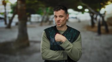 Hayır diyen genç bir adam kenar mahallede, bulanık bir şehir arka planında kendine güvenen bir yüz ifadesi sergiliyor, günlük tarzını ve dışavurumunu vurguluyor..