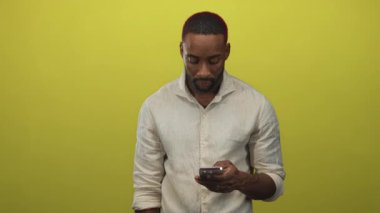 Stüdyoda elinde akıllı telefon tutan ve alnına dokunan keten gömlekli bir adam, hayal kırıklığı odaklı..