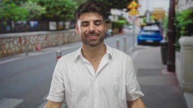 Meşgul caddede iki elle boynuz hareketi yaparken insan sırıtıyor ve dil gösteriyor..