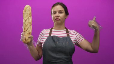 Pembe stüdyoda uzun baget tutan, eldivenli, kot önlüklü, şüpheci, hijyenik fırın hizmeti veren bir kadın..