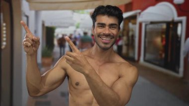 Çıplak göğüslü bir adam sabah güneşinin altında geniş bir gülümseme ve meşgul şehir caddesinde parmak işareti; güven.