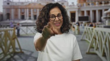 Vatikan meydanında tarihi mimari ve kalabalıklarla gülümseyen bir kadın, orta yaşlı İspanyol bir kadınla günışığında seyahat yeri sahnesi sergiliyor..