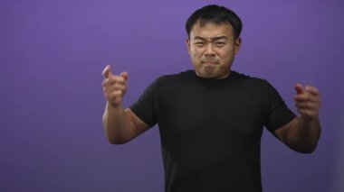 Stüdyoda mor duvara karşı sesi engellemek için her iki işaret parmağını kulaklarına bastıran adam; sinir bozucu.