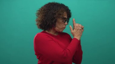 Kırmızı kazaklı kadın el ele tutuşup parmağıyla işaret ediyor..