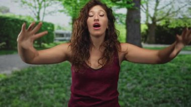 Ağzı açık, omuzları açık ve çilli genç İspanyol kadın orman parkında yol ve ağacın yanında..